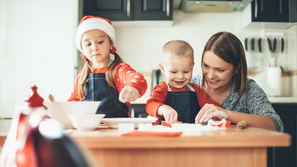 Felice famiglia caucasica preparare i biscotti per Natale a casa waring vestiti di Babbo Natale e cappello — Foto Stock