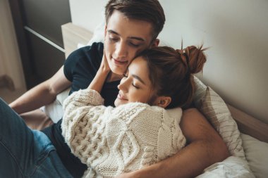 Güzel bir kadının sabah erken saatlerde sevgilisini yatakta kucaklarken çekilmiş fotoğrafı.