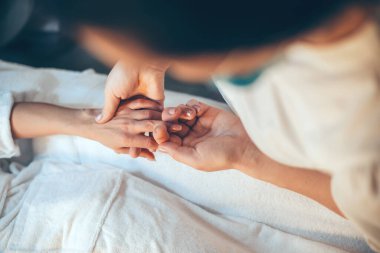 Kaplıcada uzanmış beyaz bir kadın parmak masajı yaptırıyor.