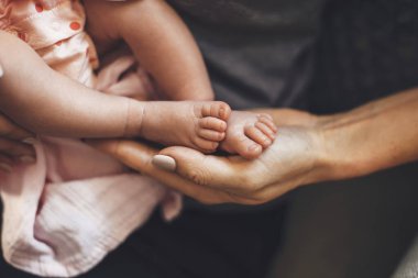 Beyaz bir ebeveyn, yeni doğmuş kızını uyurken elinde tutuyor.