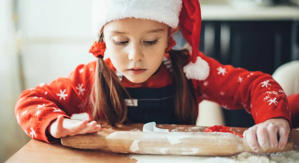 Caucásico chica está rodando la masa durante una preparación de Navidad en casa con ropa de Santa Claus —  Fotos de Stock