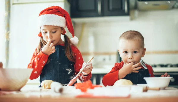 Fratello e sorella caucasici che preparano il cibo per le vacanze di Natale indossando vestiti di Babbo Natale in cucina — Foto Stock