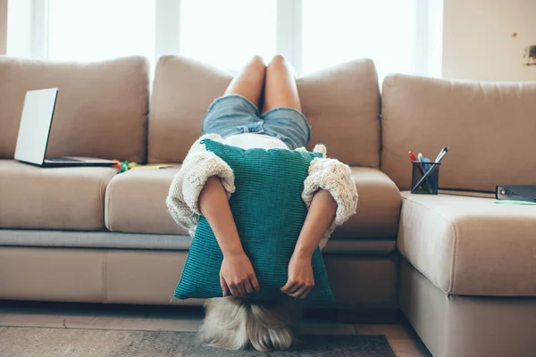 Blonde femme caucasienne couchée à l'envers sur un canapé couvrant le visage avec un oreiller se sentant fatigué aftewr travailler avec un ordinateur portable — Photo