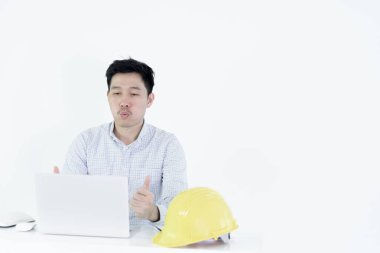 Asyalı çalışan mühendis masasında oturuyor ve başarılı ve başarılı hissederek çalışıyor, beyaz arka planda izole edilmiş..