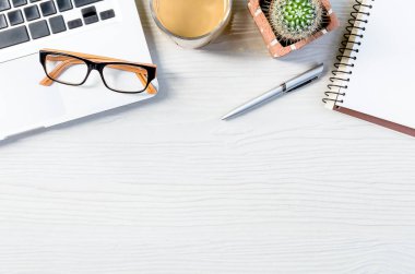 Üst görünümde çalışmak ve uzayı kopyalamak için bir sürü ekipman içeren beyaz ahşap ofis masası..