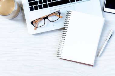 Üst görünümde çalışmak ve uzayı kopyalamak için bir sürü ekipman içeren beyaz ahşap ofis masası..