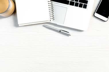 Üst görünümde çalışmak ve uzayı kopyalamak için bir sürü ekipman içeren beyaz ahşap ofis masası..