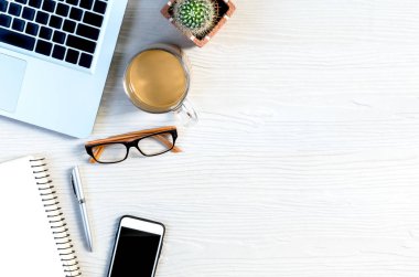 Üst görünümde çalışmak ve uzayı kopyalamak için bir sürü ekipman içeren beyaz ahşap ofis masası..