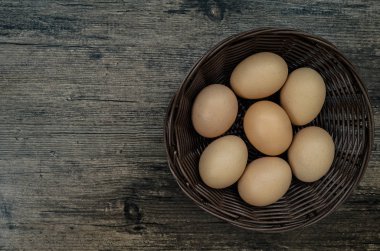 Kahverengi sepetli tavuk yumurtaları kahverengi tahta masa arkasında..