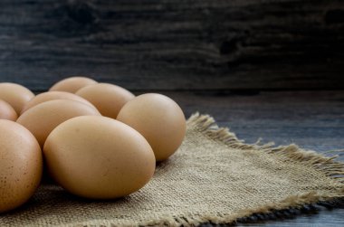 Kahverengi ahşap masa arkasında bir sürü kahverengi tavuk yumurtası..