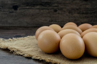 Kahverengi ahşap masa arkasında bir sürü kahverengi tavuk yumurtası..