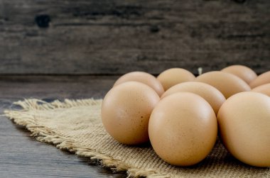 Kahverengi ahşap masa arkasında bir sürü kahverengi tavuk yumurtası..
