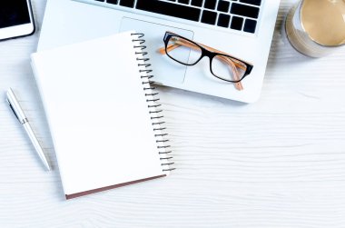 Üst görünümde çalışmak ve uzayı kopyalamak için bir sürü ekipman içeren beyaz ahşap ofis masası..