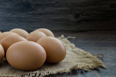 Kahverengi ahşap masa arkasında bir sürü kahverengi tavuk yumurtası..