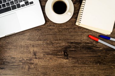 Kahverengi ahşap masa üzerinde bir kitap, kalem, kaktüs ve telefon var..