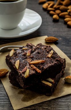 Tahta masanın üzerinde badem olan çikolatalı kek tatlı zamanında servis edilmeye hazır..