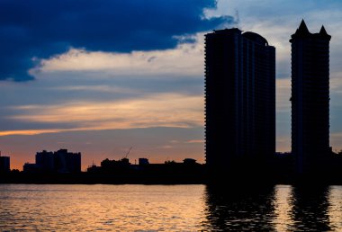 Nehir üzerinde siluet ve yansıma ile bina şehir üzerinde Gün batımı ve Bulut.