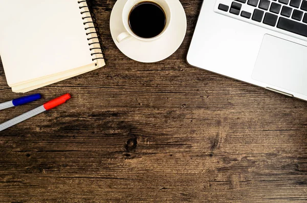 Kahverengi ahşap masa üzerinde bir kitap, kalem, kaktüs ve telefon var..