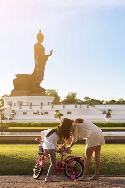 子供は乗車停止し 彼女のお母さんは夕方に Phutthamonthon 公共公園でリラックスした時間に彼女の足をチェックしています — ストック写真