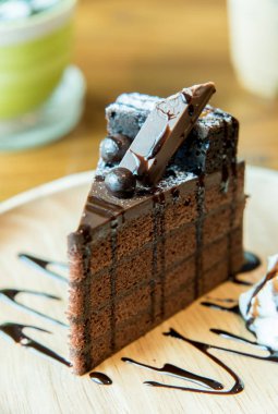 Gofret ve ahşap plaka üzerinde krema ile çikolatalı kek servis etmeye hazır.