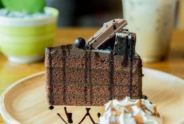 Gofret ve ahşap plaka üzerinde krema ile çikolatalı kek servis etmeye hazır.