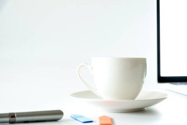 Kahve Fincanı ve beyaz ofis masası üzerinde bilgisayar masaüstü gümüş kalem ve not ile sabah çalışma için closeup görünümü ve kopya alanı conecpt.