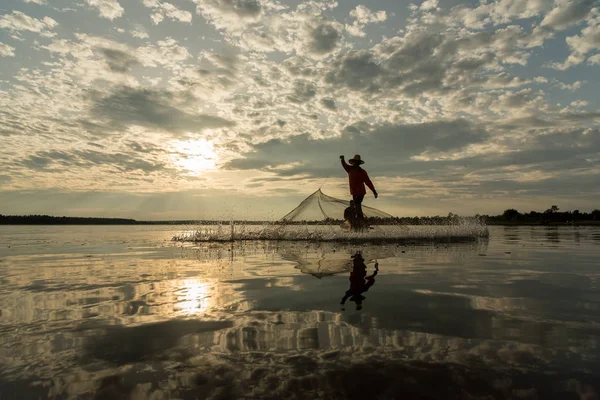 Silhouette of Fishermen throwing net fishing in sunset time at Wanon Niwat district Sakon Nakhon Northeast Thailand.