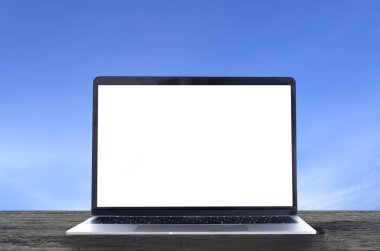 Ahşap masada beyaz beyaz ekranlı ve mavi gökyüzü arkaplanlı bir laptop. Bilgisayar kavramına bilgisayar veri yedeği.
