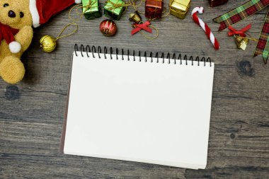 Noel ayısı ve beyaz kitap. Kahverengi ahşap masa üzerindeki boşluğu kopyalayın. Noel festivali konsepti.