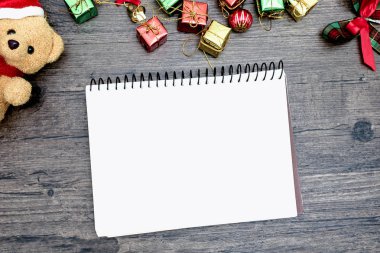 Noel ayısı ve beyaz kitap. Kahverengi ahşap masa üzerindeki boşluğu kopyalayın. Noel festivali konsepti.