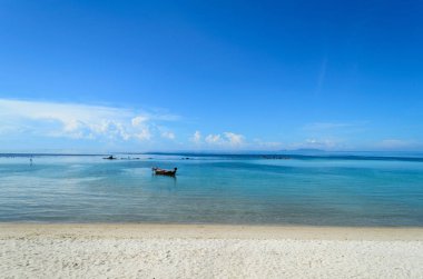 Sabah mavi gökyüzünün altında tekne ve deniz manzarası.