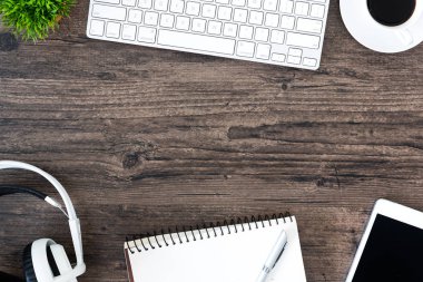 Kahverengi ahşap ofis masası ve çalışma ve dinleme ekipmanları beyaz kulaklıklı üst görünümde ve boşluğu kopyalamak için.