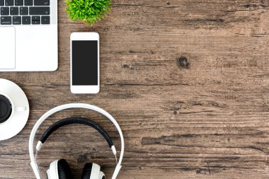 Kahverengi ahşap ofis masası ve çalışma ve dinleme ekipmanları beyaz kulaklıklı üst görünümde ve boşluğu kopyalamak için.