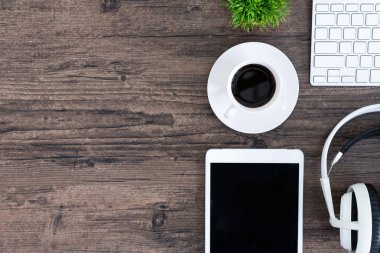 Kahverengi ahşap ofis masası ve çalışma ve dinleme ekipmanları beyaz kulaklıklı üst görünümde ve boşluğu kopyalamak için.