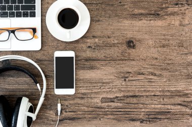 Kahverengi ahşap ofis masası ve çalışma ve dinleme ekipmanları beyaz kulaklıklı üst görünümde ve boşluğu kopyalamak için.