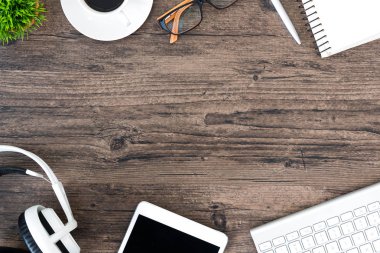 Kahverengi ahşap ofis masası ve çalışma ve dinleme ekipmanları beyaz kulaklıklı üst görünümde ve boşluğu kopyalamak için.