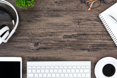 Kahverengi ahşap ofis masası ve çalışma ve dinleme ekipmanları beyaz kulaklıklı üst görünümde ve boşluğu kopyalamak için.