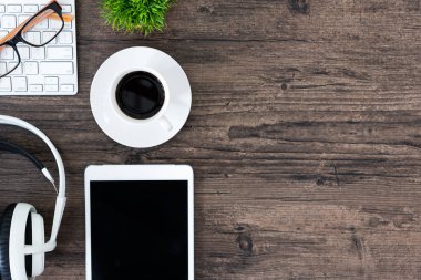 Kahverengi ahşap ofis masası ve çalışma ve dinleme ekipmanları beyaz kulaklıklı üst görünümde ve boşluğu kopyalamak için.