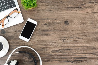 Kahverengi ahşap ofis masası ve çalışma ve dinleme ekipmanları beyaz kulaklıklı üst görünümde ve boşluğu kopyalamak için.