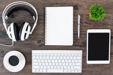 Kahverengi ahşap ofis masası ve çalışma ve dinleme ekipmanları beyaz kulaklıklı üst görünümde ve boşluğu kopyalamak için.