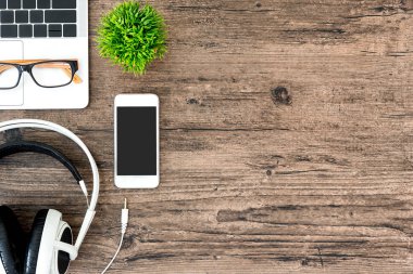 Kahverengi ahşap ofis masası ve çalışma ve dinleme ekipmanları beyaz kulaklıklı üst görünümde ve boşluğu kopyalamak için.