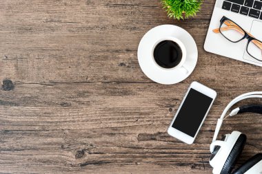 Kahverengi ahşap ofis masası ve çalışma ve dinleme ekipmanları beyaz kulaklıklı üst görünümde ve boşluğu kopyalamak için.