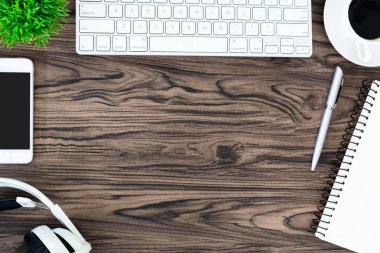 Kahverengi ahşap ofis masası ve çalışma ve dinleme ekipmanları beyaz kulaklıklı üst görünümde ve boşluğu kopyalamak için.