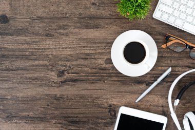 Kahverengi ahşap ofis masası ve çalışma ve dinleme ekipmanları beyaz kulaklıklı üst görünümde ve boşluğu kopyalamak için.