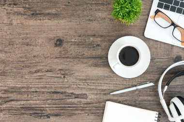 Kahverengi ahşap ofis masası ve çalışma ve dinleme ekipmanları beyaz kulaklıklı üst görünümde ve boşluğu kopyalamak için.