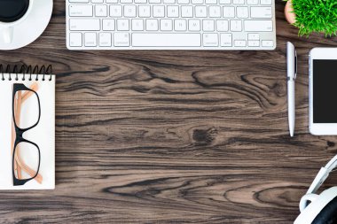 Kahverengi ahşap ofis masası ve çalışma ve dinleme ekipmanları beyaz kulaklıklı üst görünümde ve boşluğu kopyalamak için.