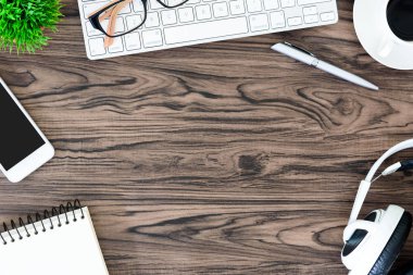 Kahverengi ahşap ofis masası ve çalışma ve dinleme ekipmanları beyaz kulaklıklı üst görünümde ve boşluğu kopyalamak için.