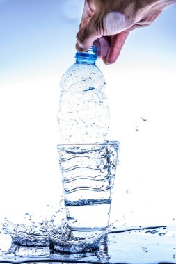 Su dolu bardaktaki boş şişe, su sıçratıyor ve yansıtıyor..