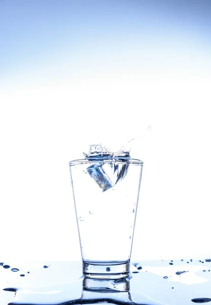 冰滴和水飞溅在玻璃上 镜面桌上反射 白色背景隔离 — 图库照片