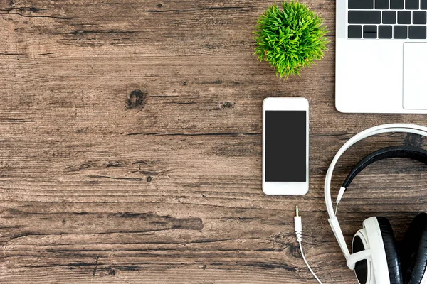 Kahverengi ahşap ofis masası ve çalışma ve dinleme ekipmanları beyaz kulaklıklı üst görünümde ve boşluğu kopyalamak için.